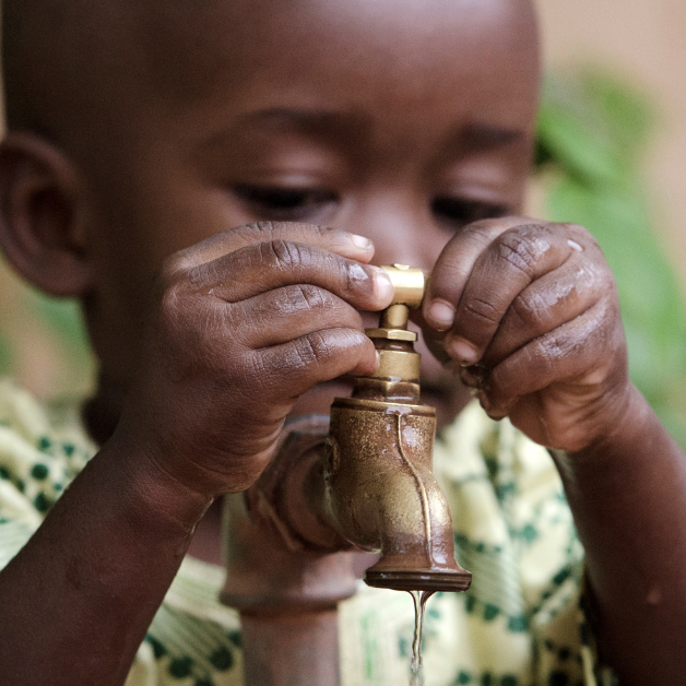 Get Involved A young boy holds his face close to a dripping water faucet