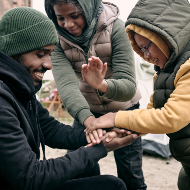 Get Involved 3 A young man plays a hand game with two other young boys in the street